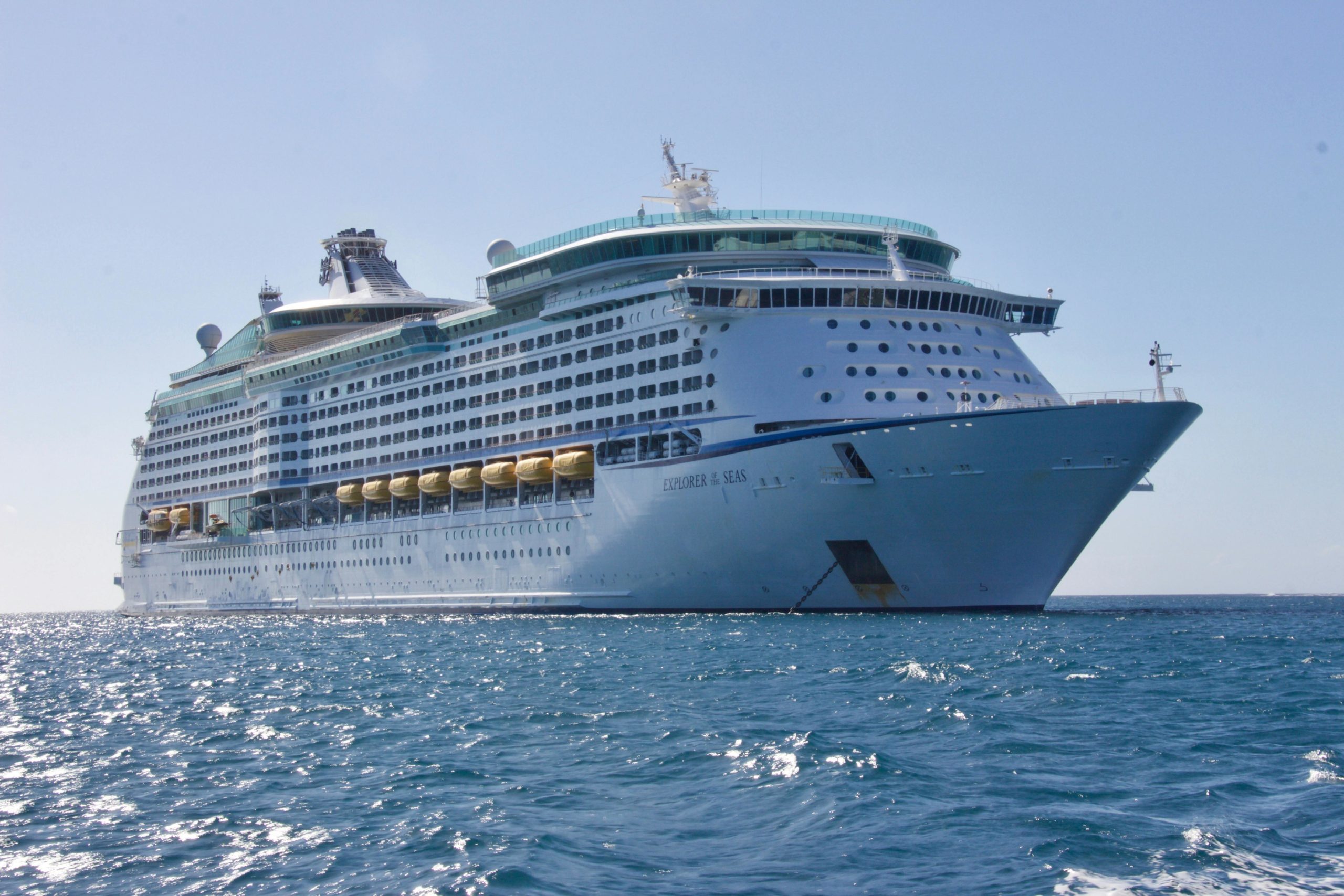 A large cruise ship named Explorer of the Seas sailing on a calm sea under a clear blue sky.